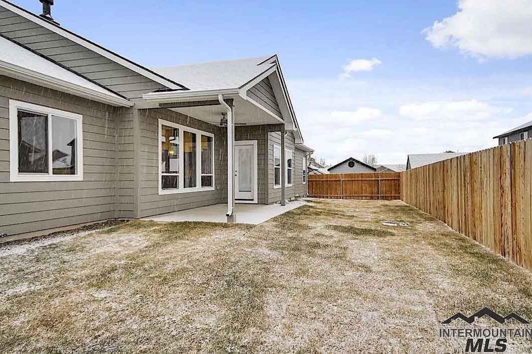 The backyard of a house with a wooden fence and a covered porch.