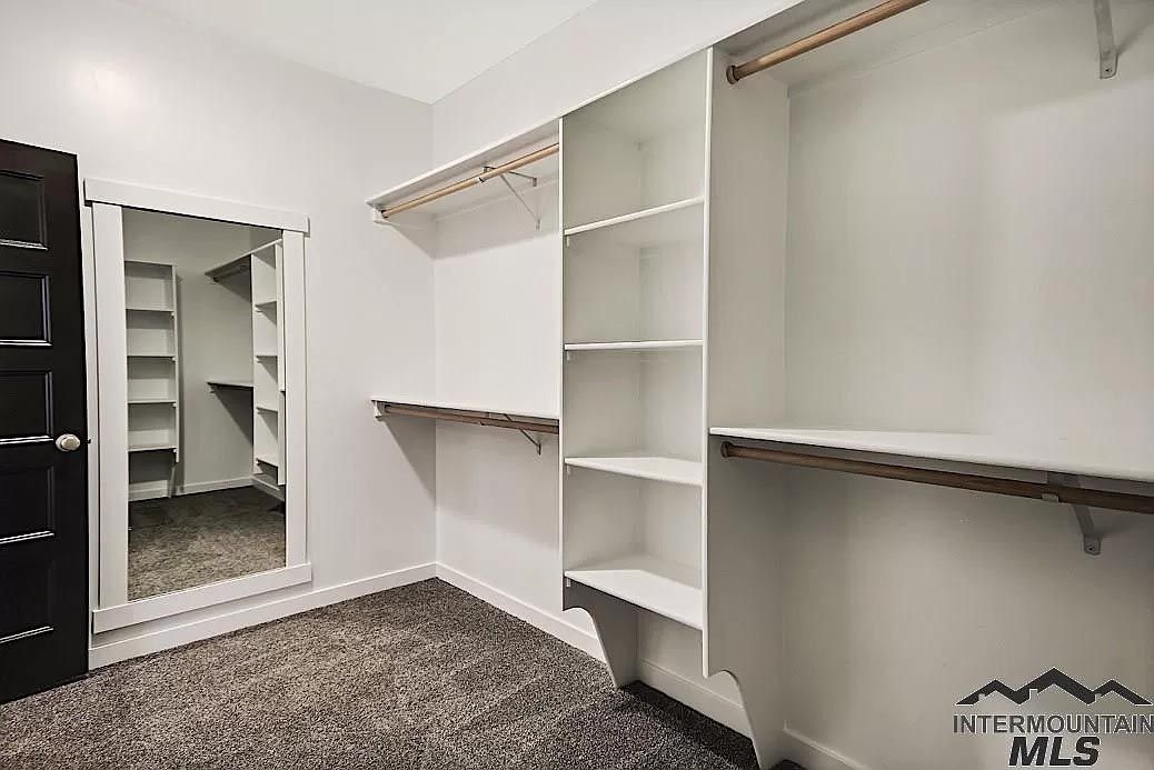 A walk in closet with lots of shelves and a mirror.
