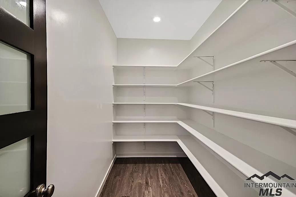 A walk in pantry with lots of shelves and a wooden floor.
