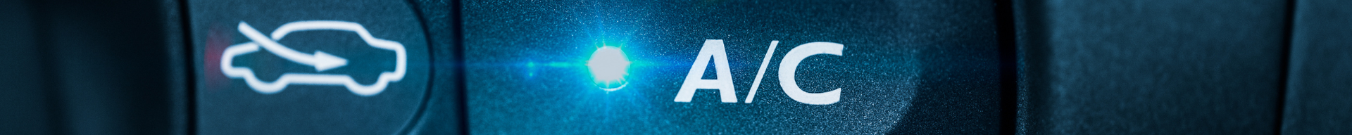 Vehicle A/C control button illuminated on a dashboard, representing air conditioning operation