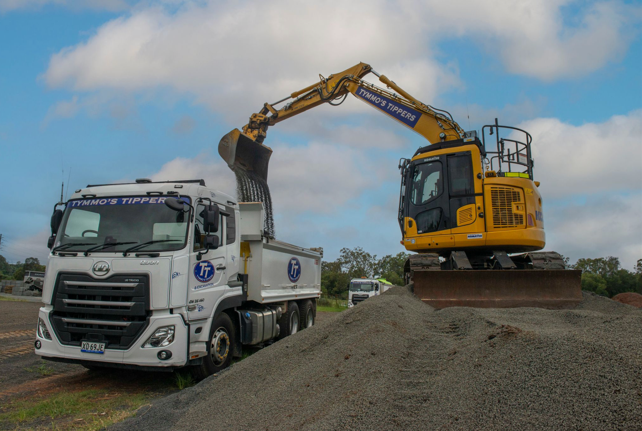 A Yellow Excavator Is On A Pile Of Dirt Loading Dirt Into A Truck— Tymmo's Tippers In West Ballina, NSW