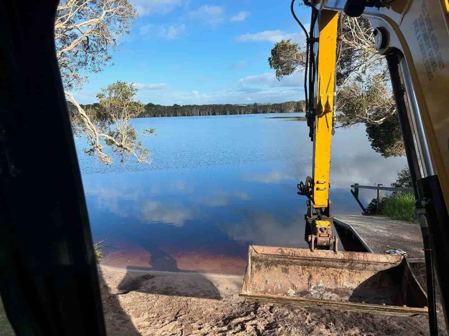 A Yellow Excavator Is Working On A Beach Next To A Lake — Tymmo's Tippers In Mullumbimby, NSW