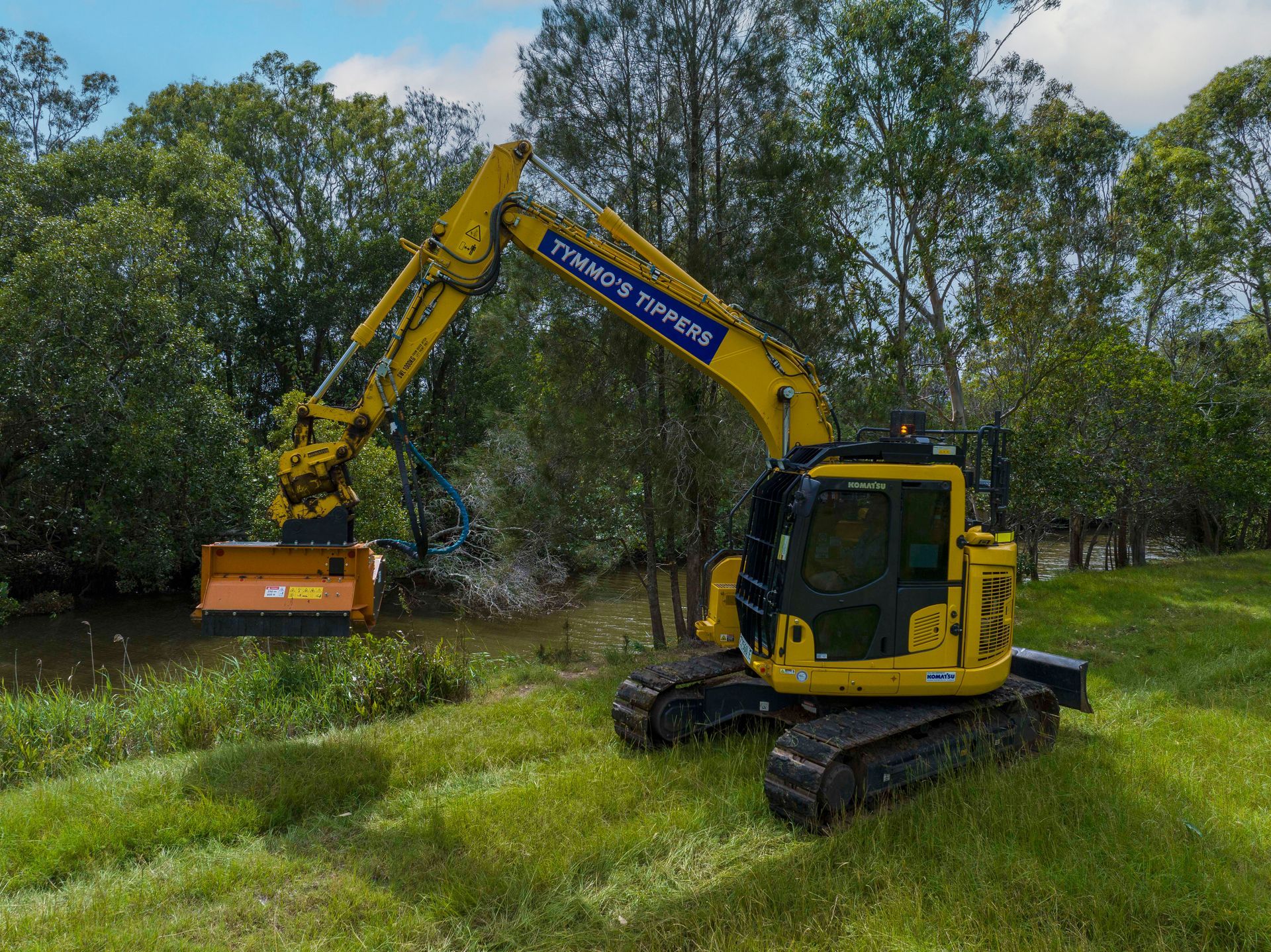 A Yellow Excavator Clearing Trees In A Field — Tymmo's Tippers In West Ballina, NSW