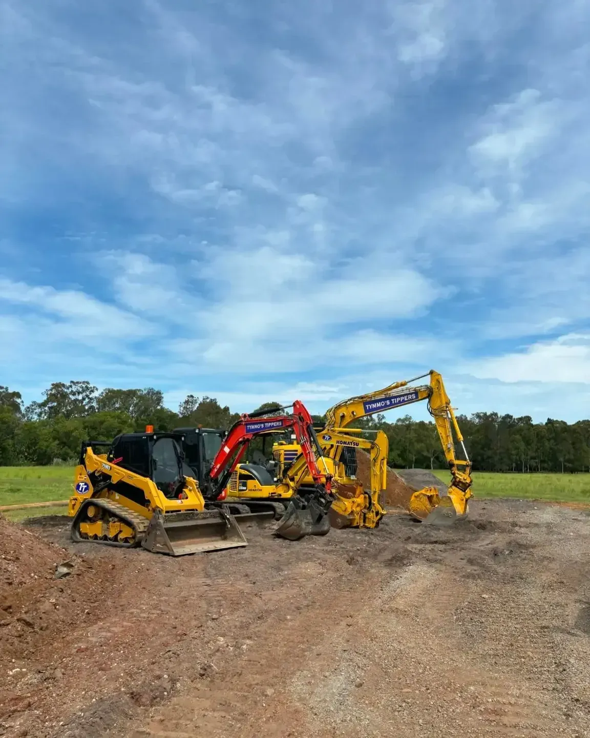 A Group Of Construction Vehicles Are Parked In A Dirt Field — Tymmo's Tippers In Ballina, NSW