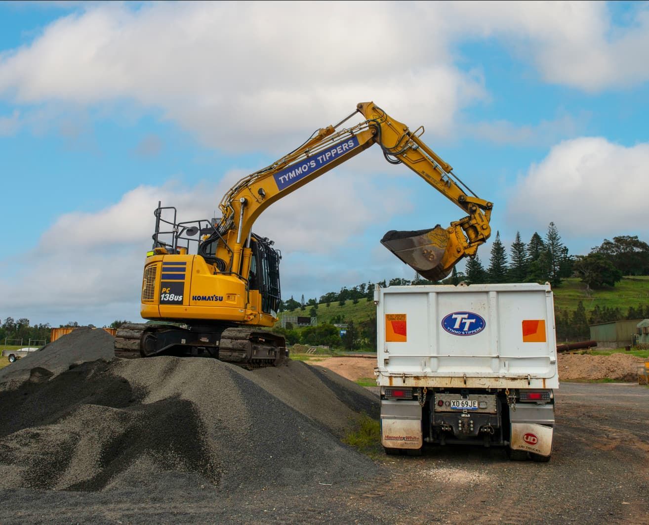 A Yellow Excavator Is Loading Gravel Into A Dump Truck — Tymmo's Tippers In Kingscliff, NSW