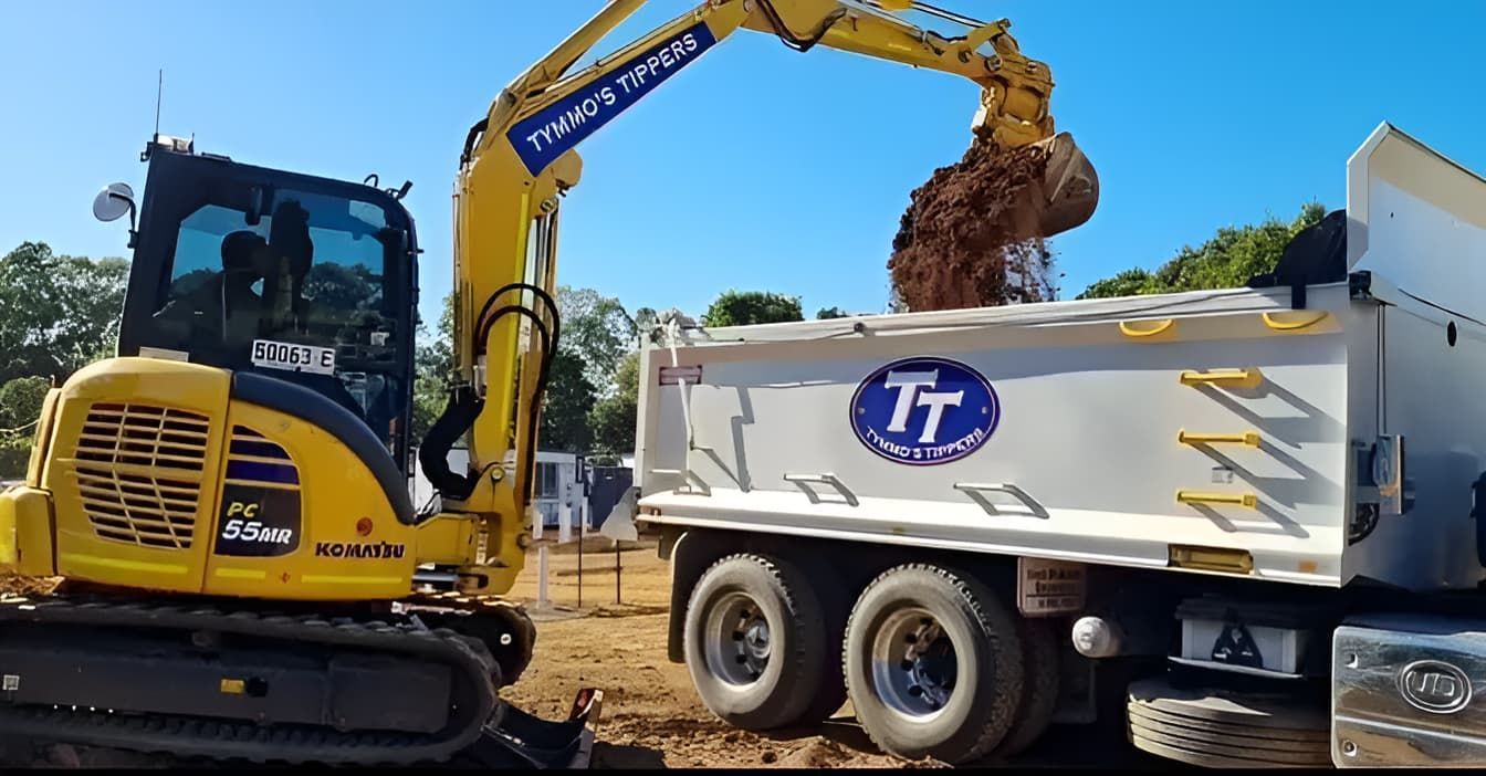 A Yellow Excavator Is Loading Dirt Into A Dump Truck — Tymmo's Tippers In Lismore, NSW