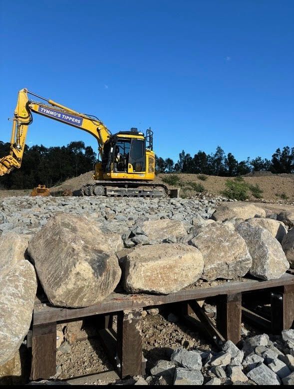 A Yellow Excavator Is Working On A Pile Of Rocks — Tymmo's Tippers In Evans Head, NSW
