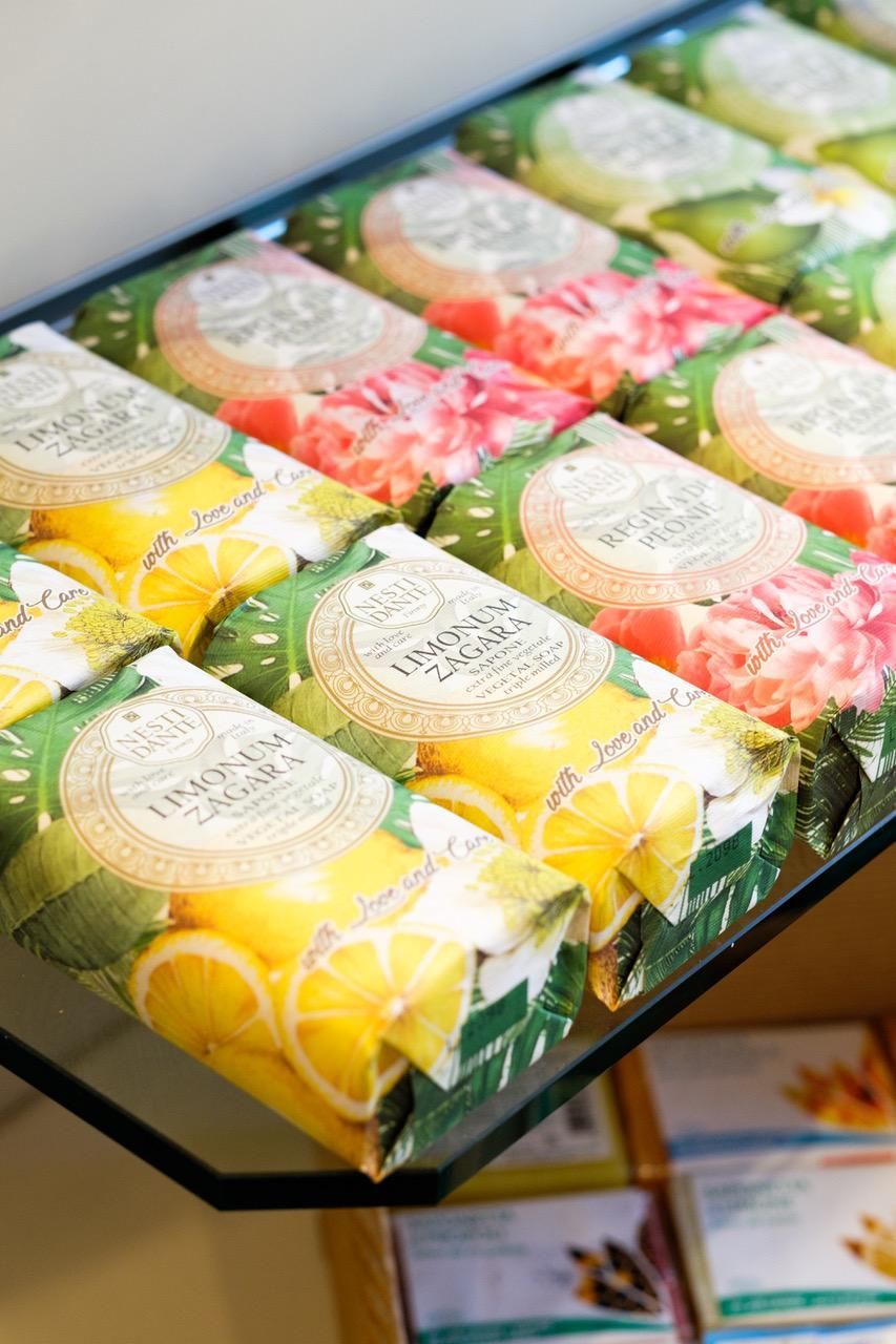 Vetrina di saponi colorati incartati; confezioni gialle, rosa e verdi.