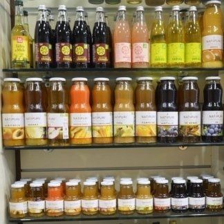 Scaffali pieni di bottiglie di succhi di frutta assortiti, in vari colori, dimensioni e gusti.