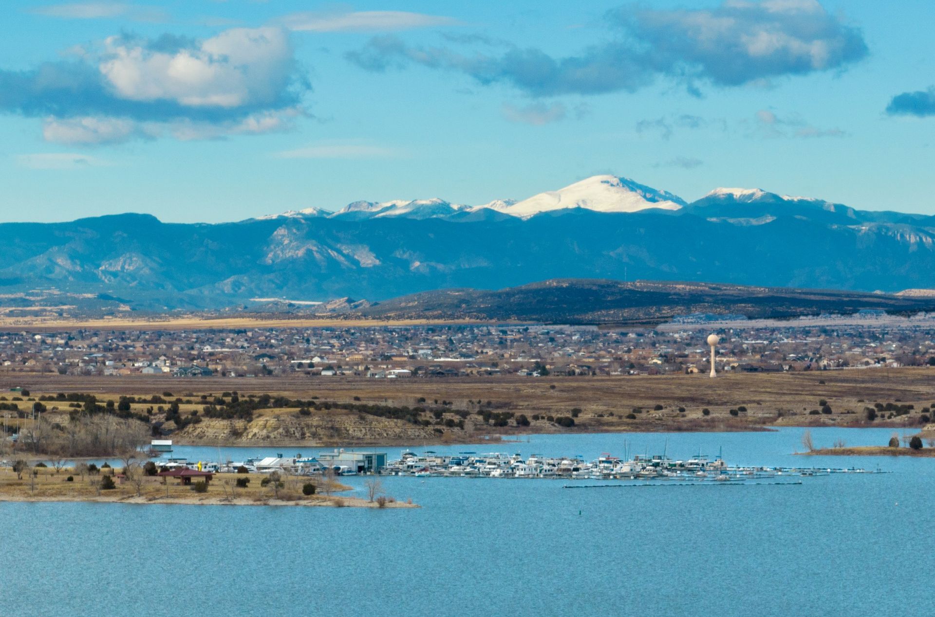 A lake with mountains in the background and a city in the foreground.