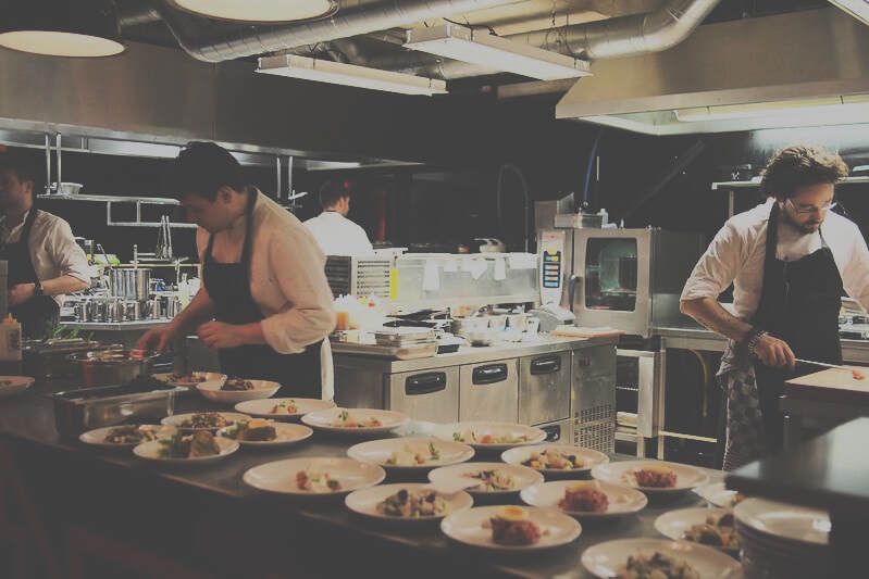 Chefs preparing plates in a restaurant kitchen with stainless steel equipment
