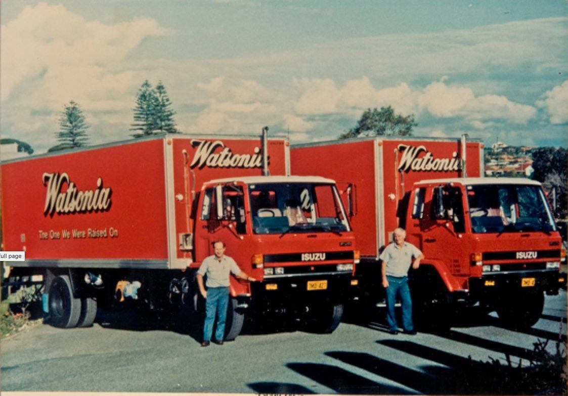 Two men are standing in front of two red trucks