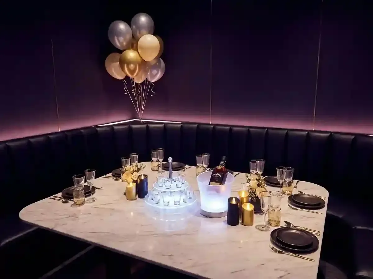 Elegant banquet table with gold balloons and candlelit place settings in a dim purple booth