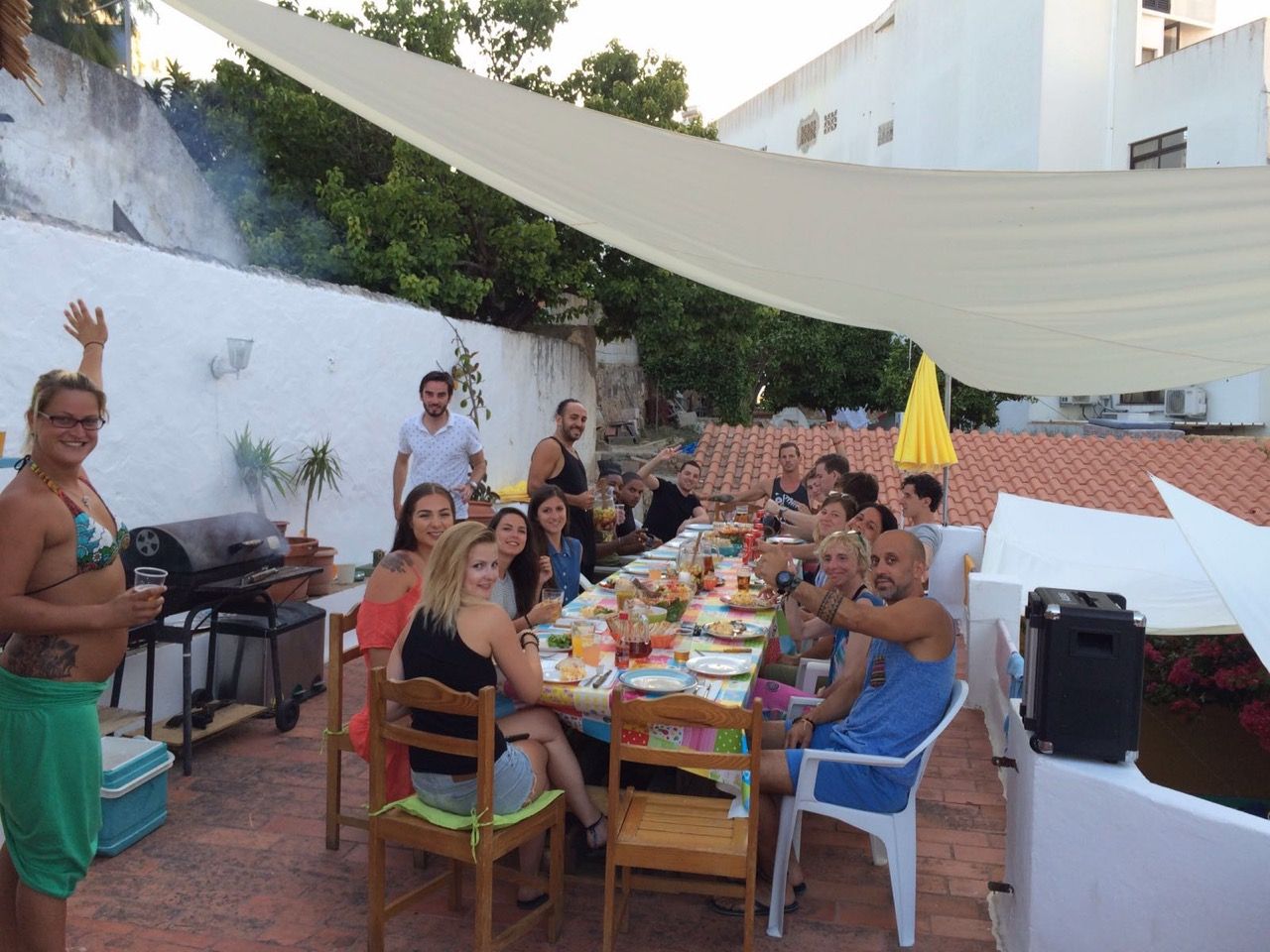 a group of people are sitting around a long table in Orange Terrace Hostel  patio