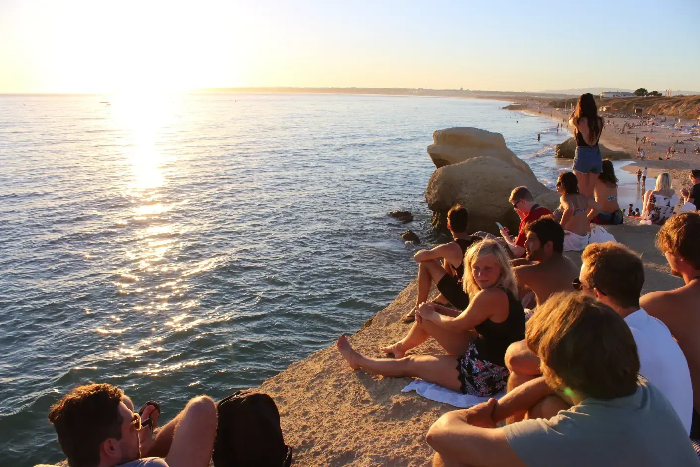a group of people are sitting on a rock overlooking the ocean .