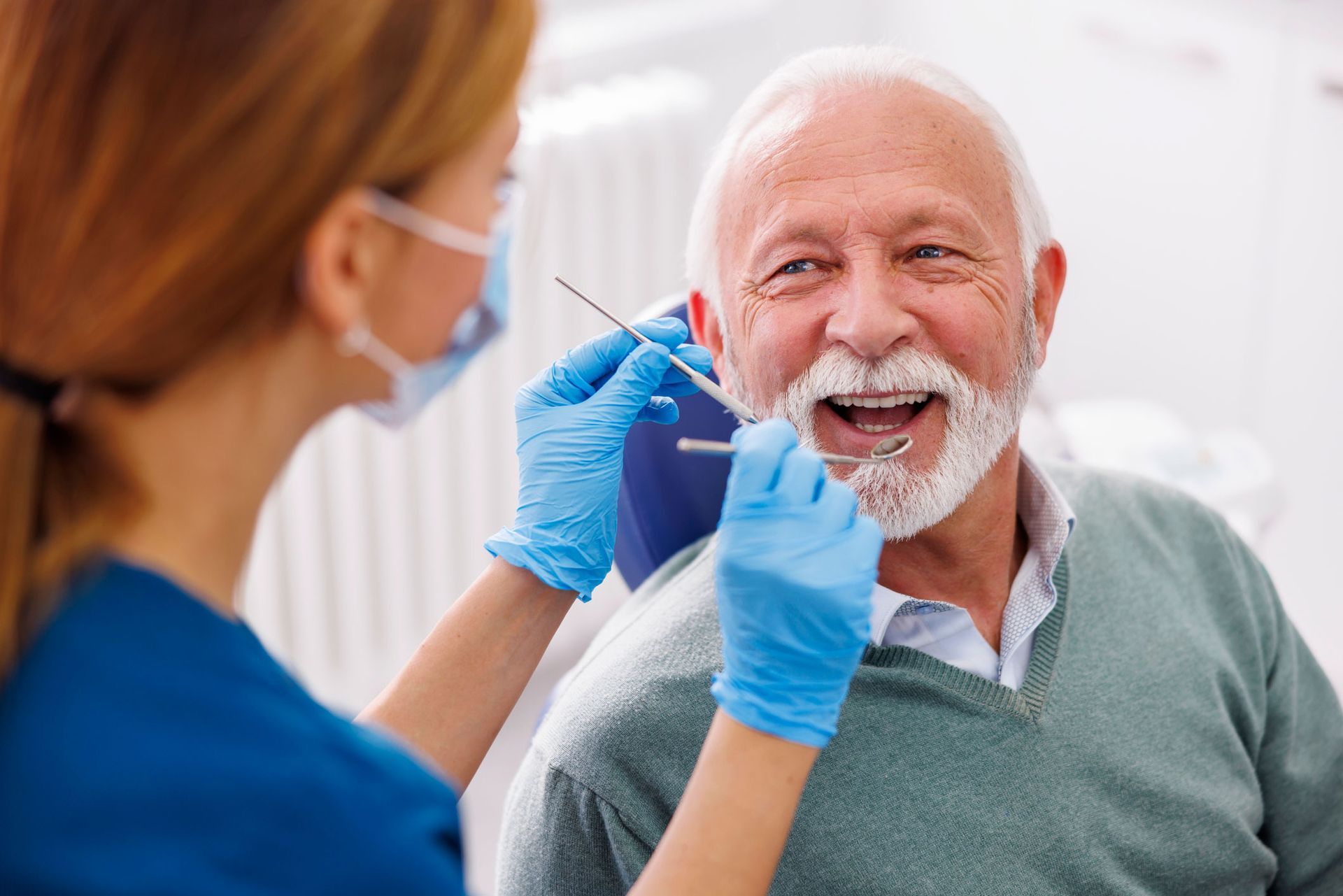 An elderly man is having his teeth examined by a dentist.