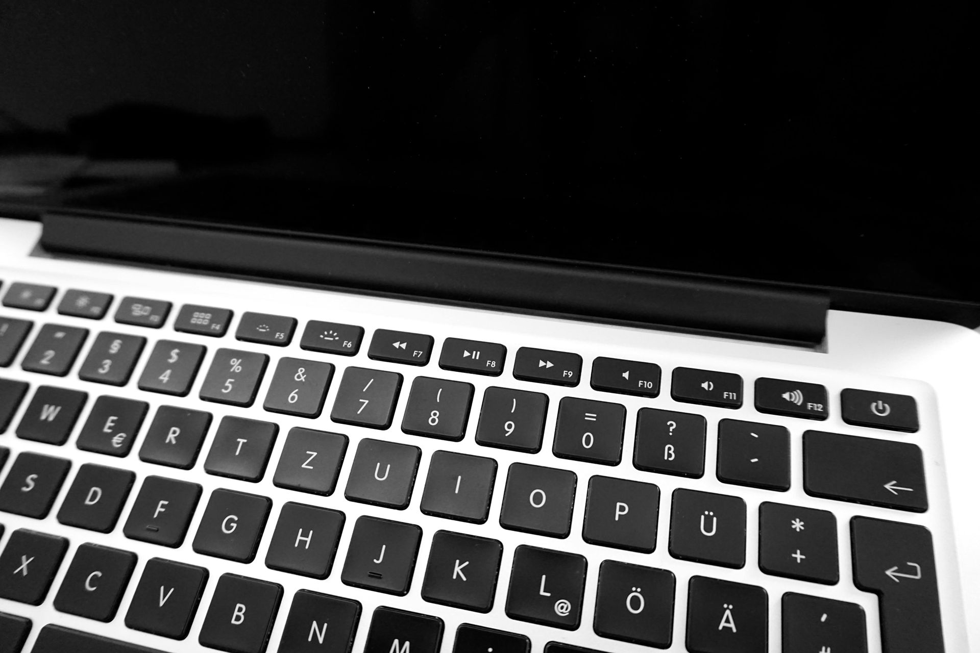 Close-up of a laptop keyboard and screen in black and white.