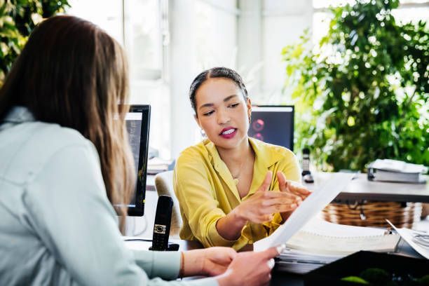 A woman is looking at some paperwork with a colleague.