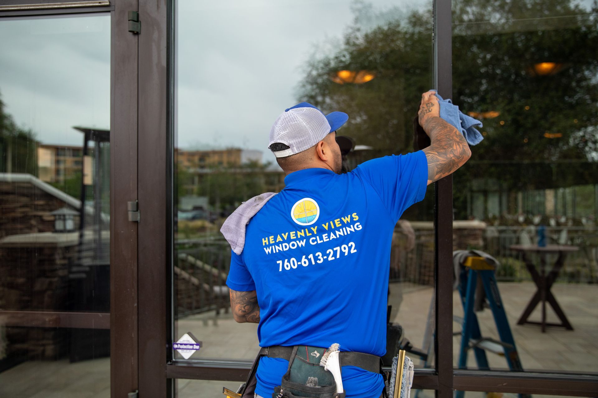 Worker in blue shirt cleaning a glass storefront window