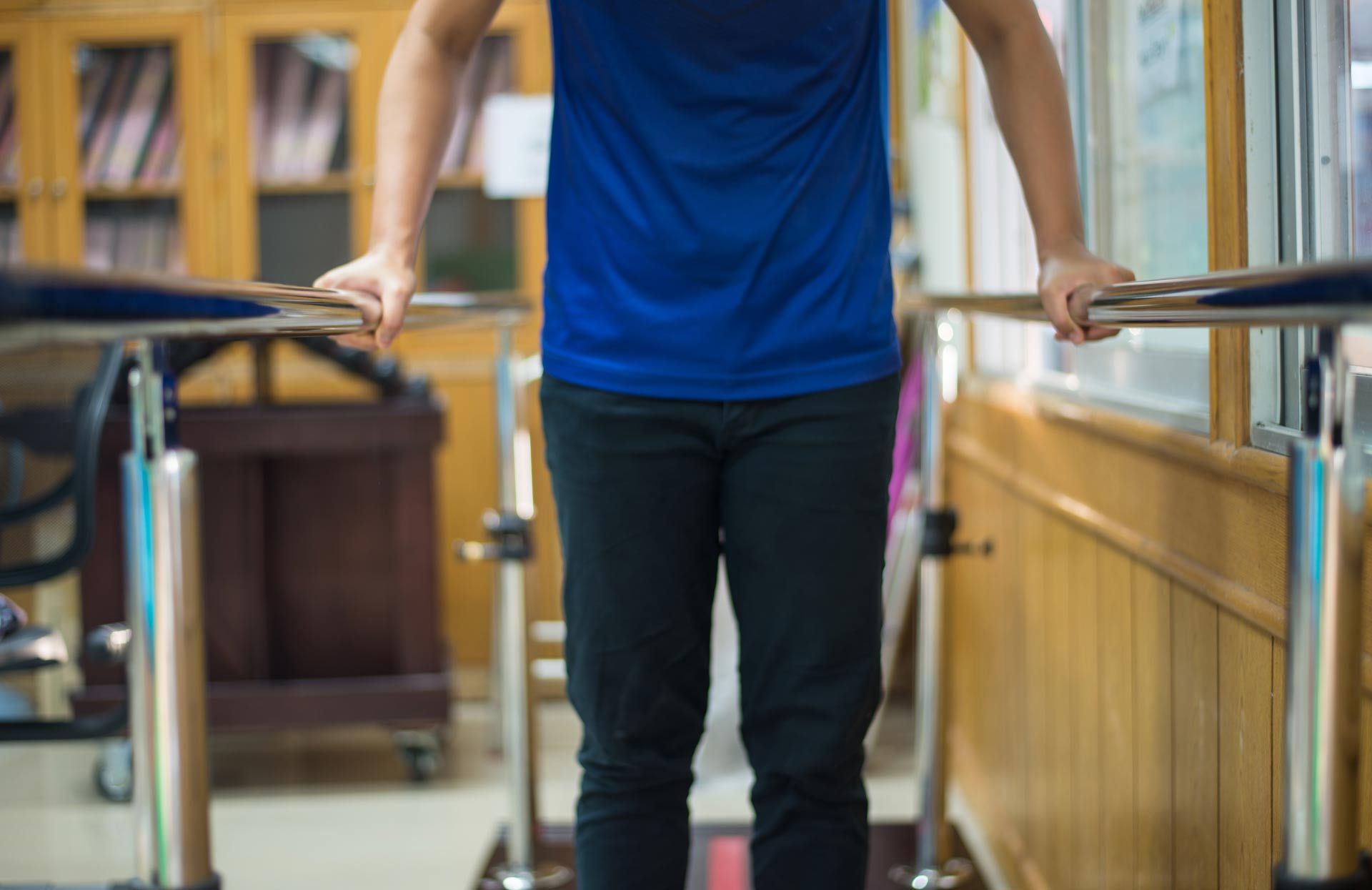A man is standing on parallel bars in a hospital.