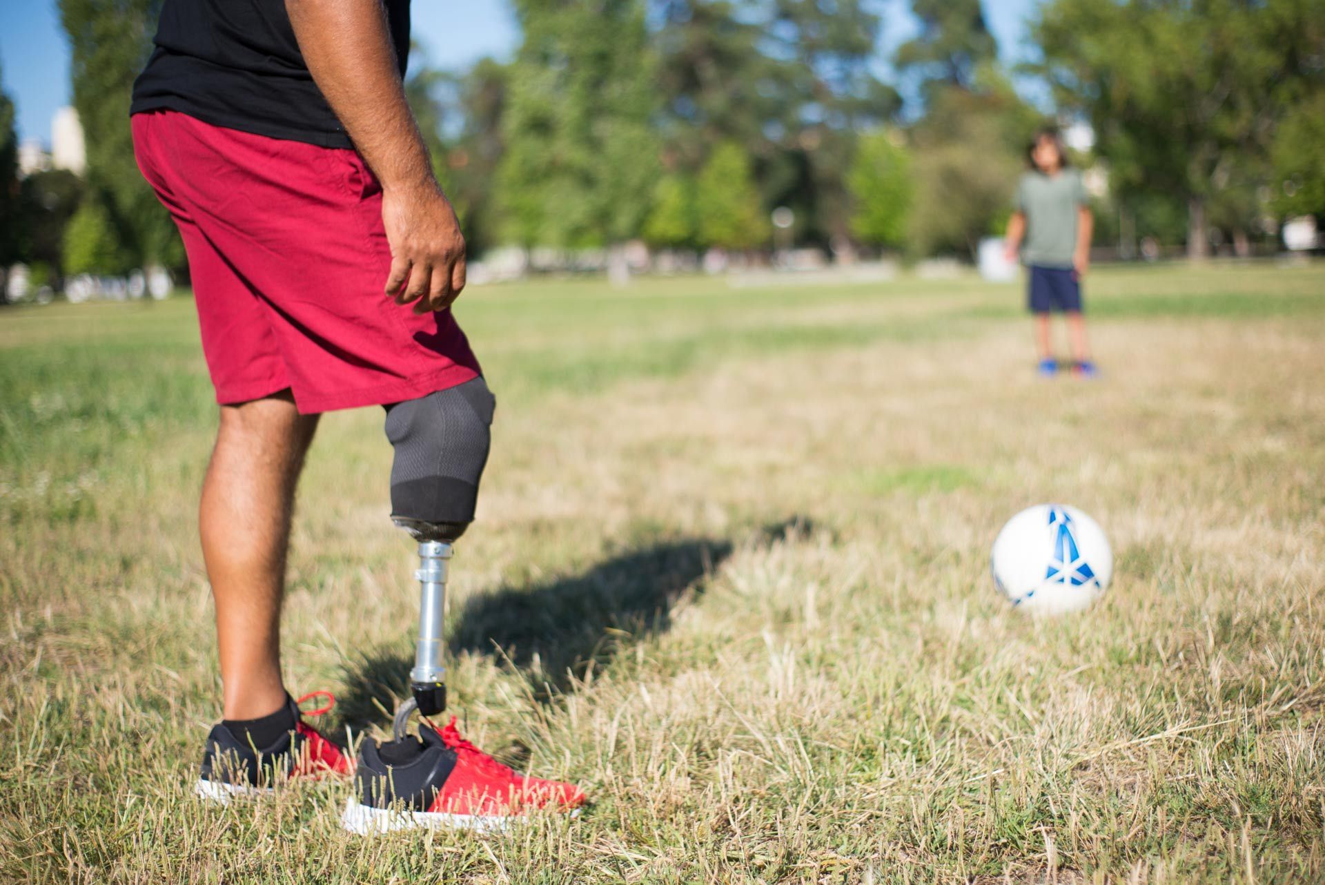 A man with a prosthetic leg is playing soccer in a field.