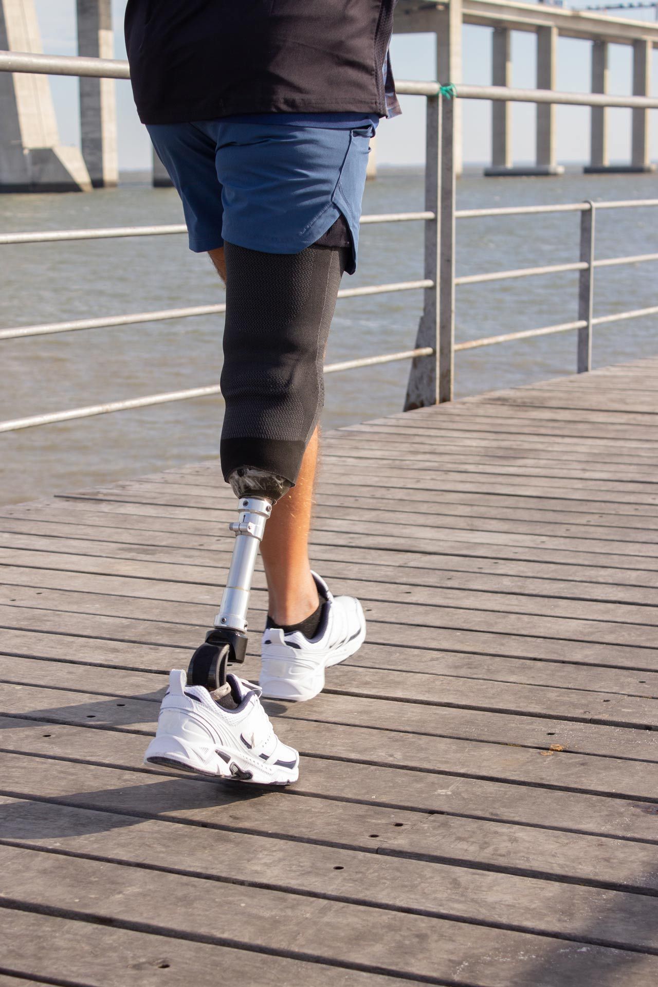 A person with a prosthetic leg is walking on a pier.