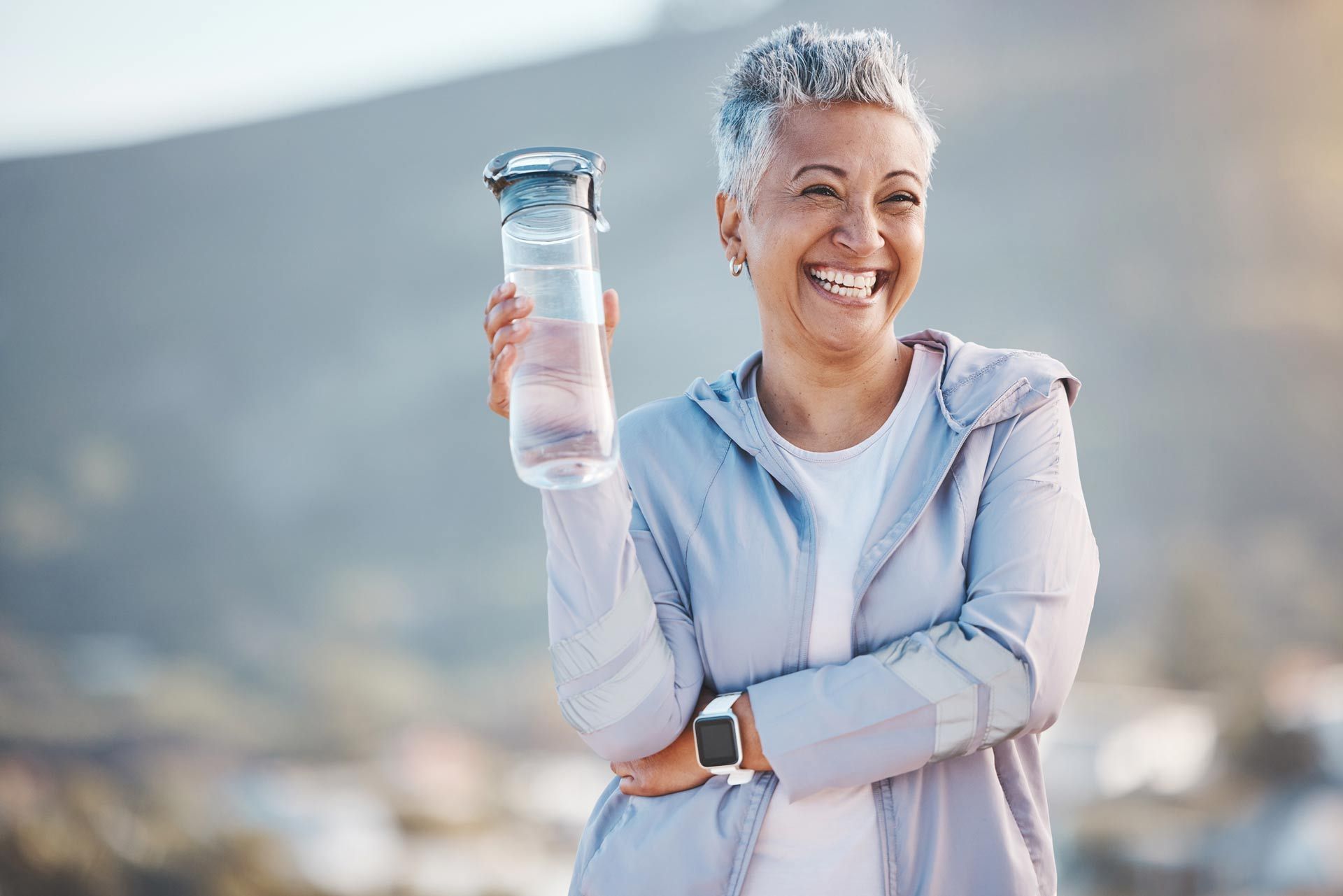 A woman is holding a bottle of water and smiling.