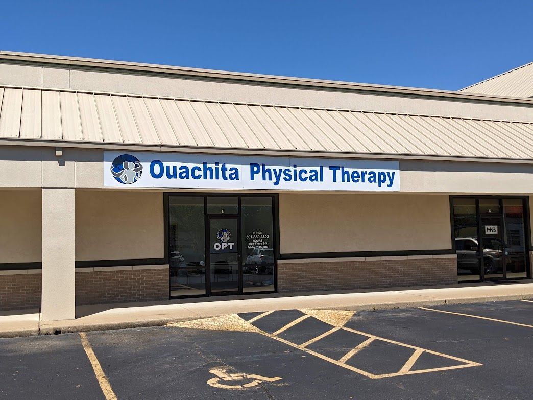 A white building with a blue sign that says ouachita physical therapy