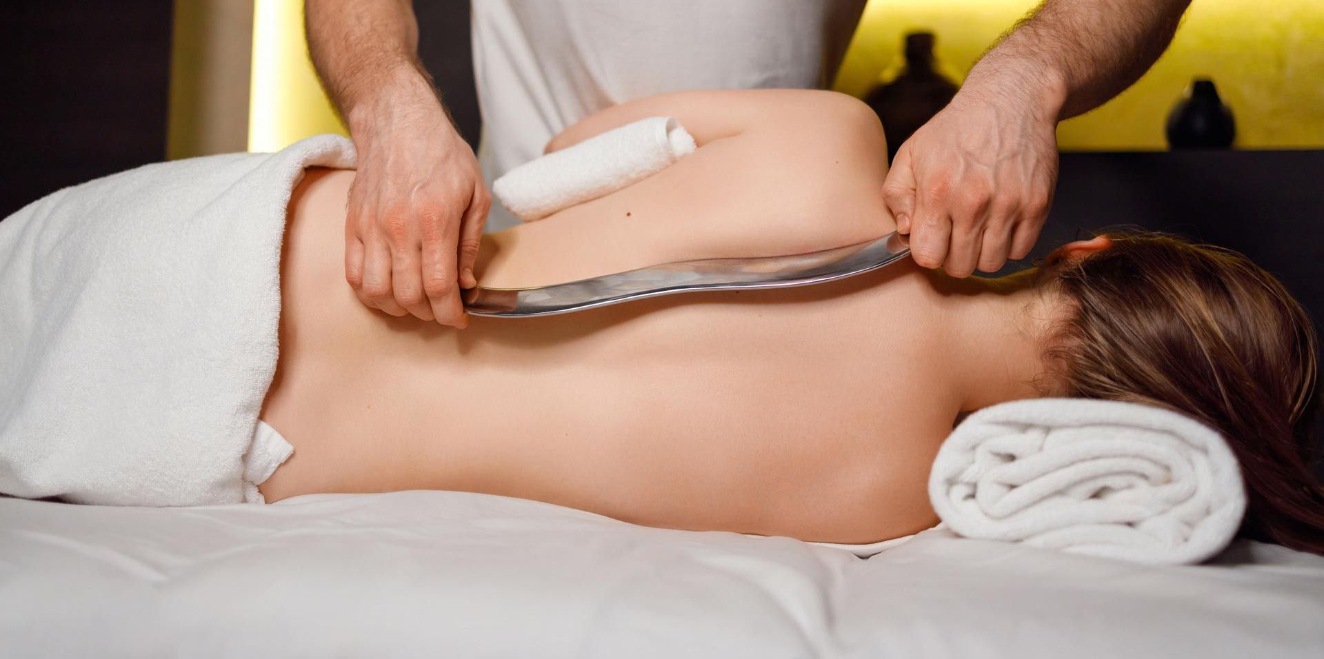 A woman is laying on a bed getting a massage from a man.