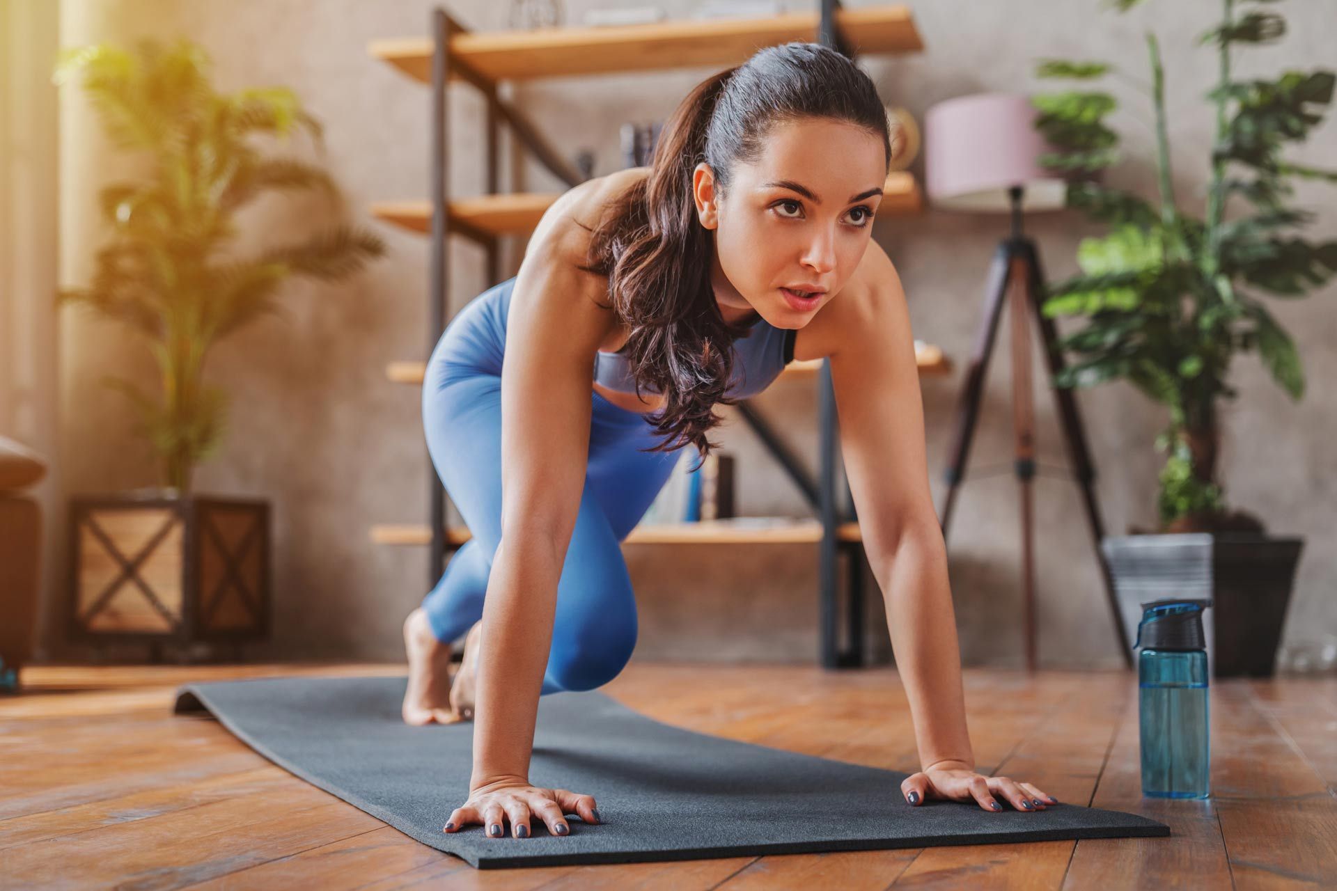 A woman is doing push ups on a yoga mat in a living room.