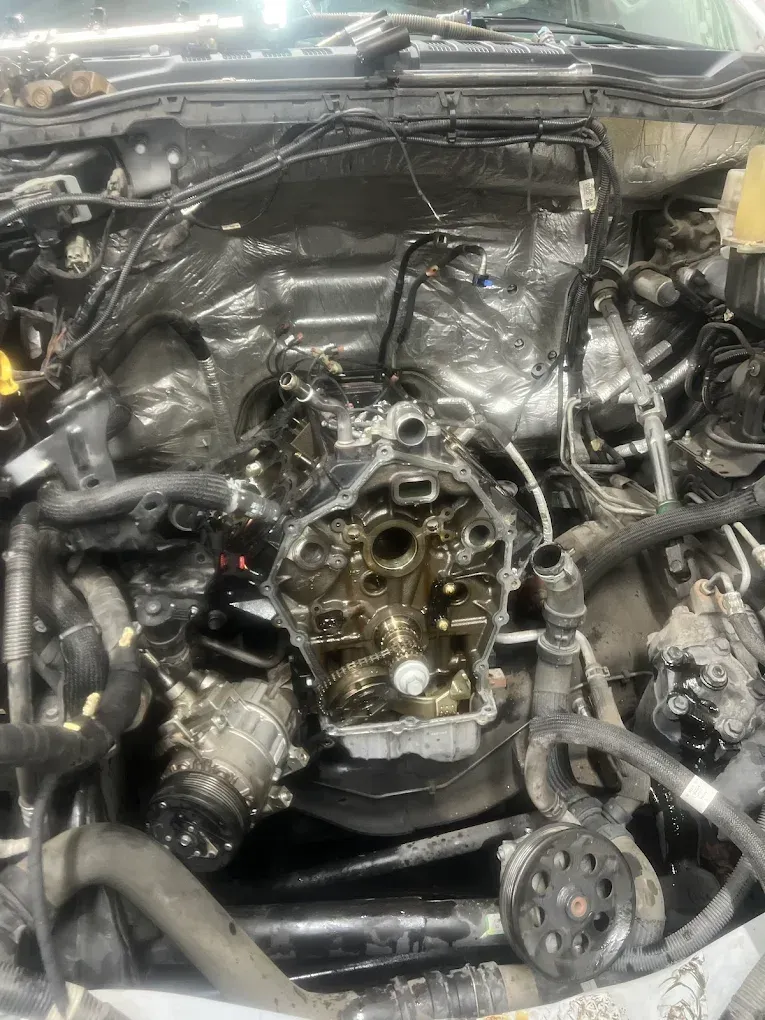 Car engine with the top open, showing internal components and oil.