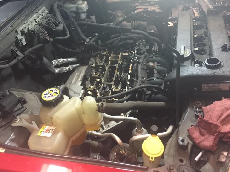 Car engine with open top, showing internal components during repair.