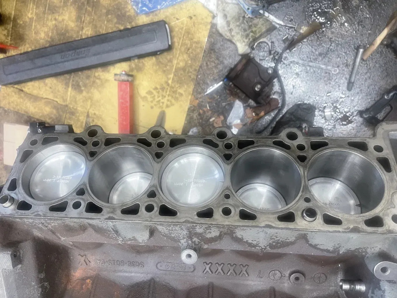 Engine block with visible pistons inside cylinders, in a workshop setting.