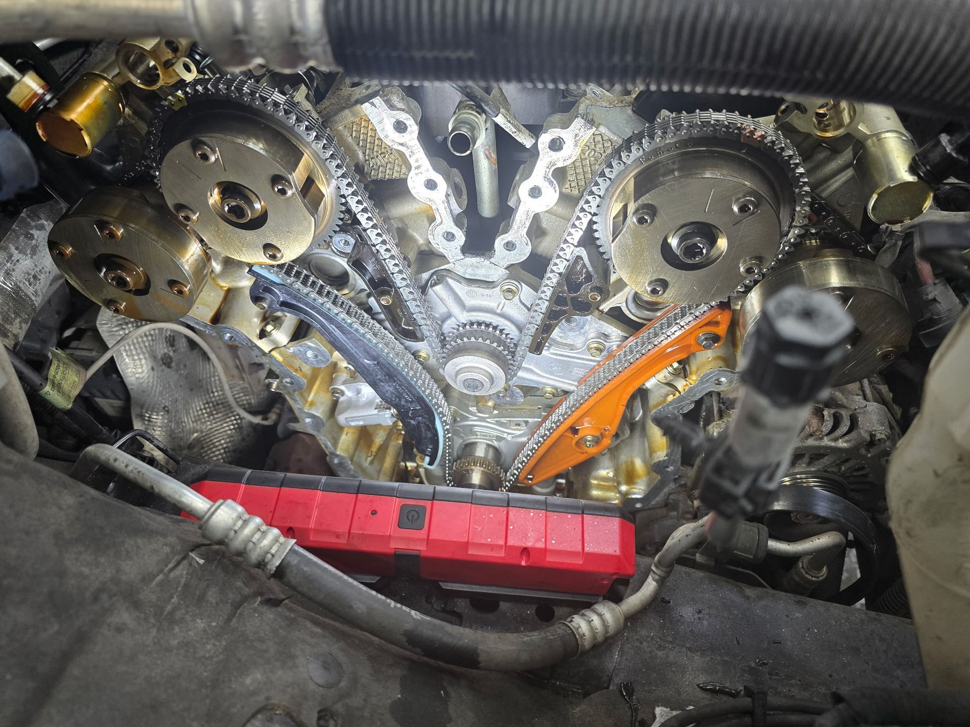 Engine's internal components, with timing chains and gears exposed, viewed from above, in a repair setting.