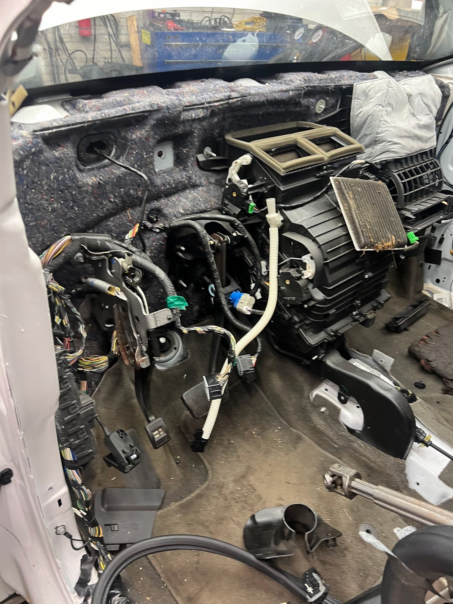 Interior of a car with dashboard and components removed, revealing wiring, air conditioning unit, and floor.