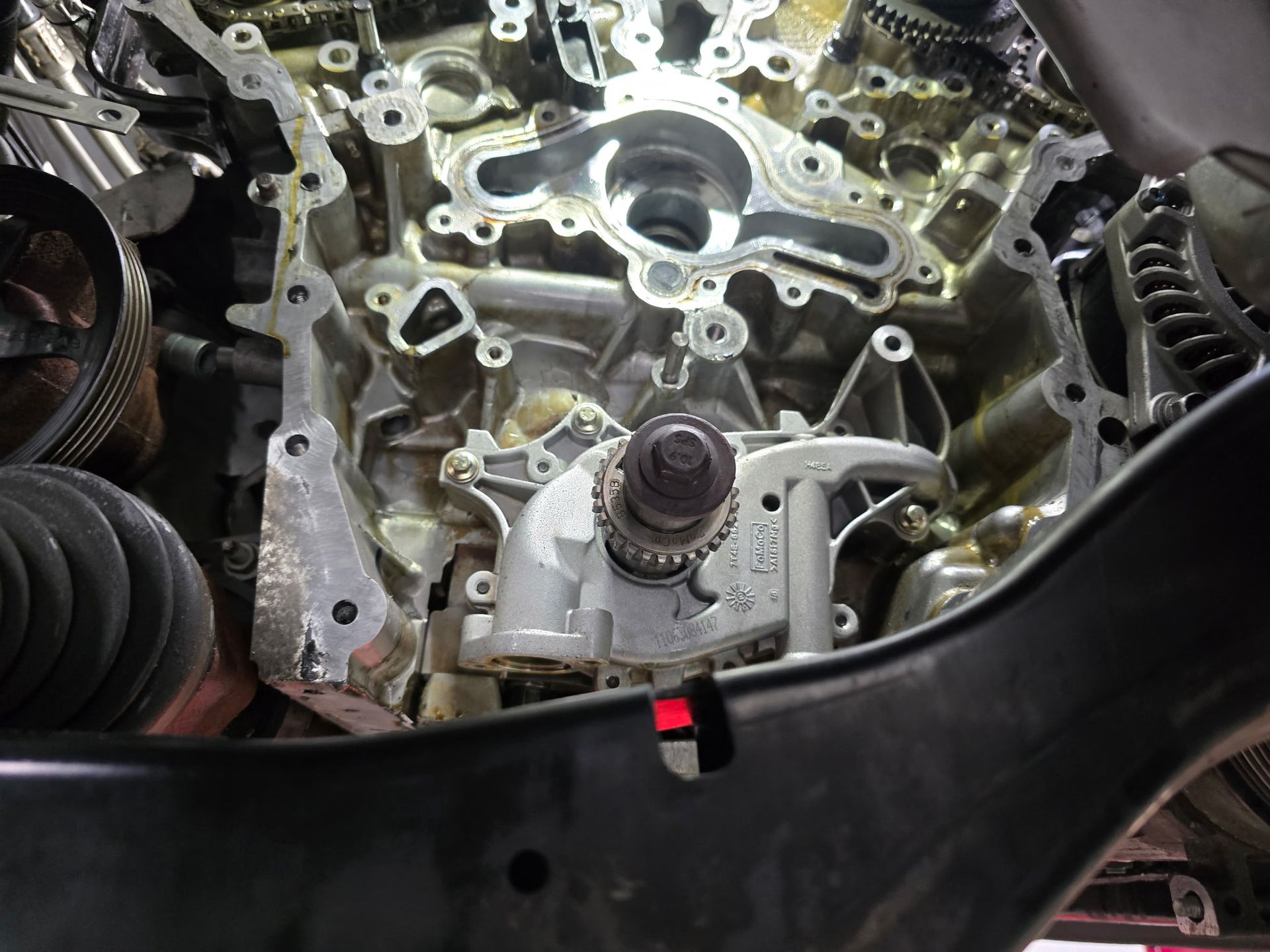 Engine components with a water pump in place, viewed from below, inside a car.