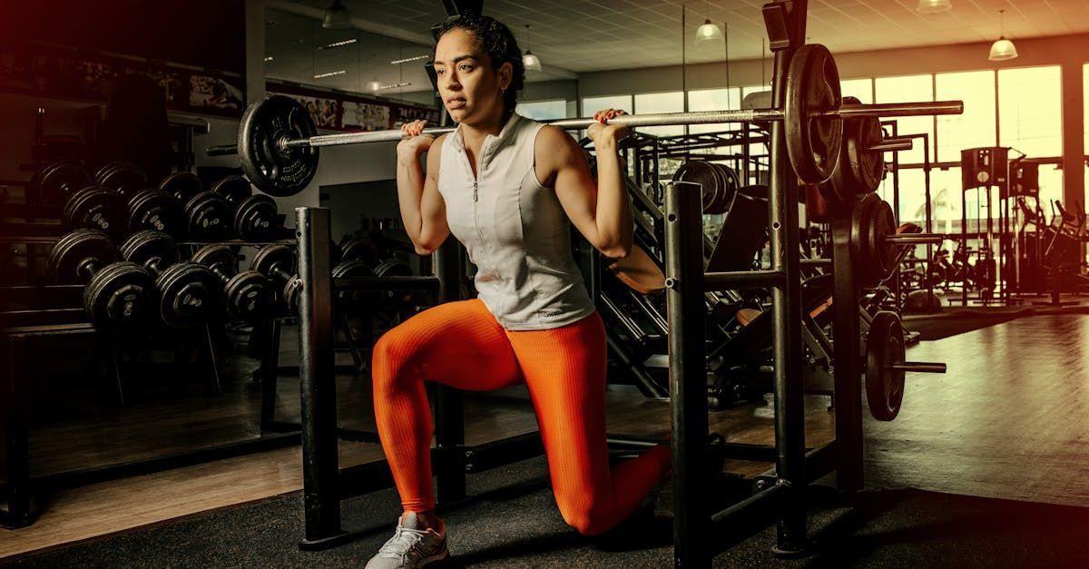 A woman is squatting with a barbell in a gym.