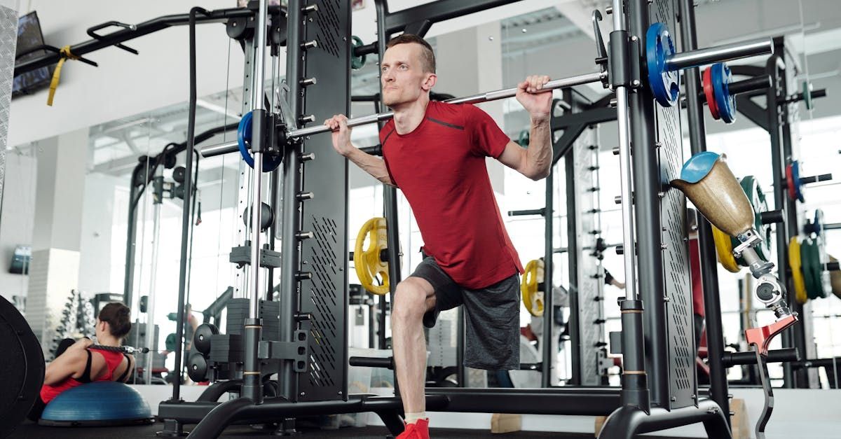 A man is squatting with a barbell in a gym.