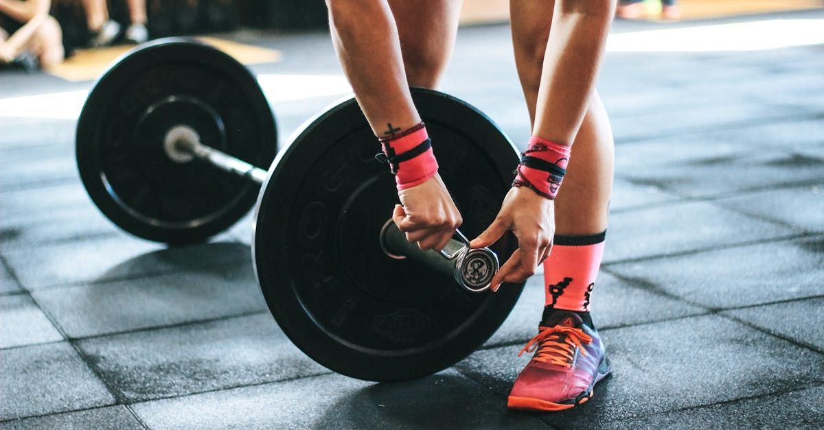 A woman is lifting a barbell in a gym.