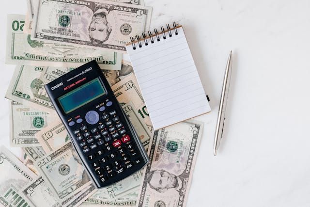 calculator and notepad on a pile of money