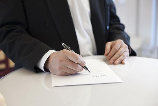 Person signing a contract at a round table.
