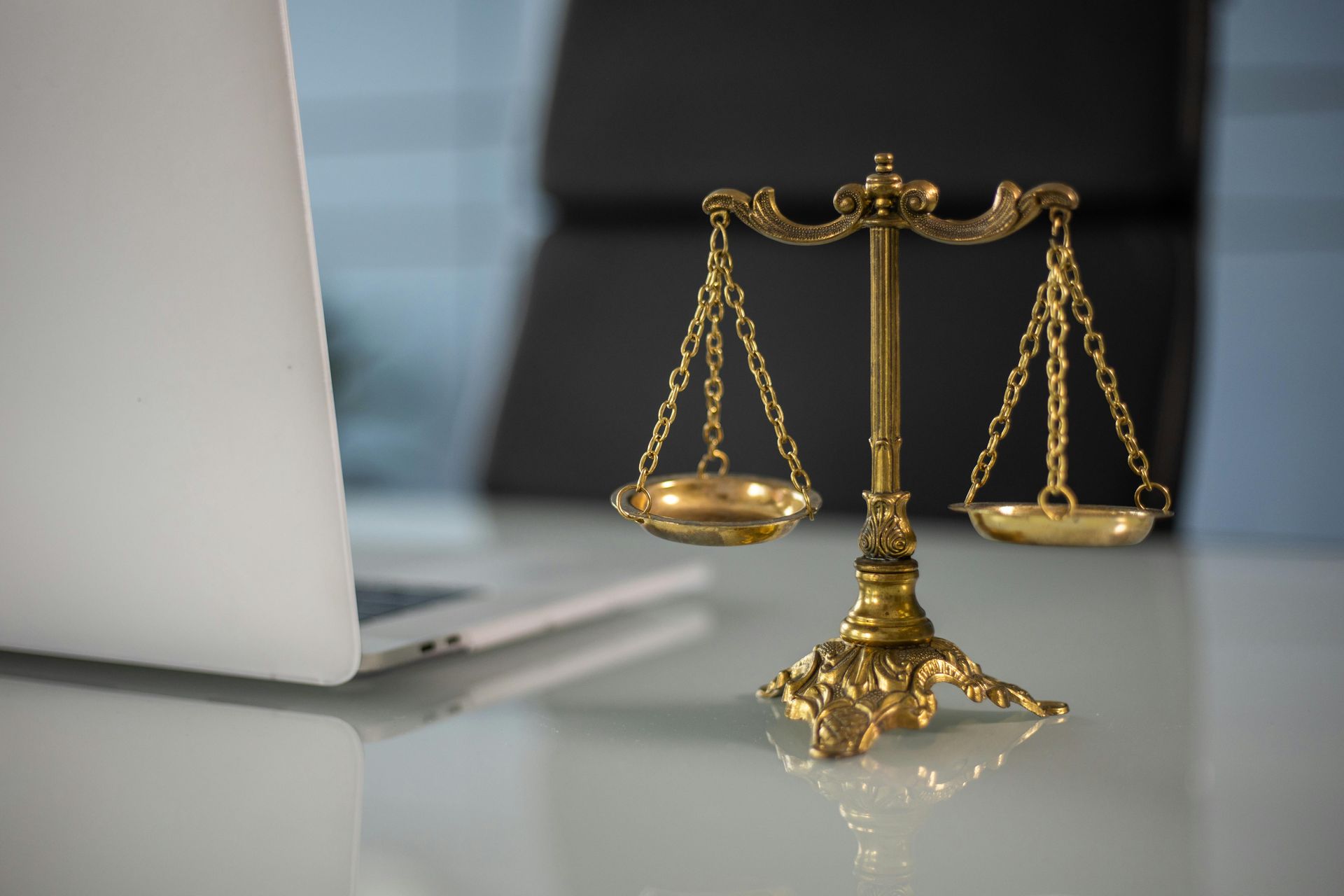 scales of justice on a desk next to an open laptop