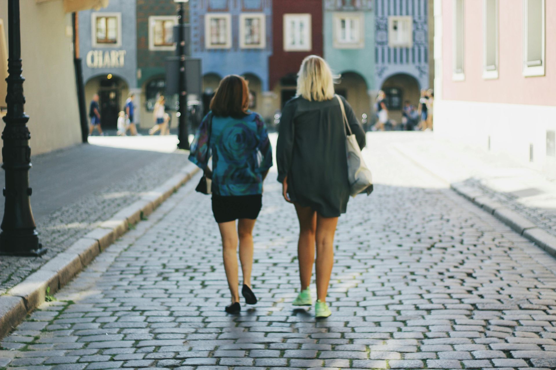 Two people walking down a street lined by old buildings.