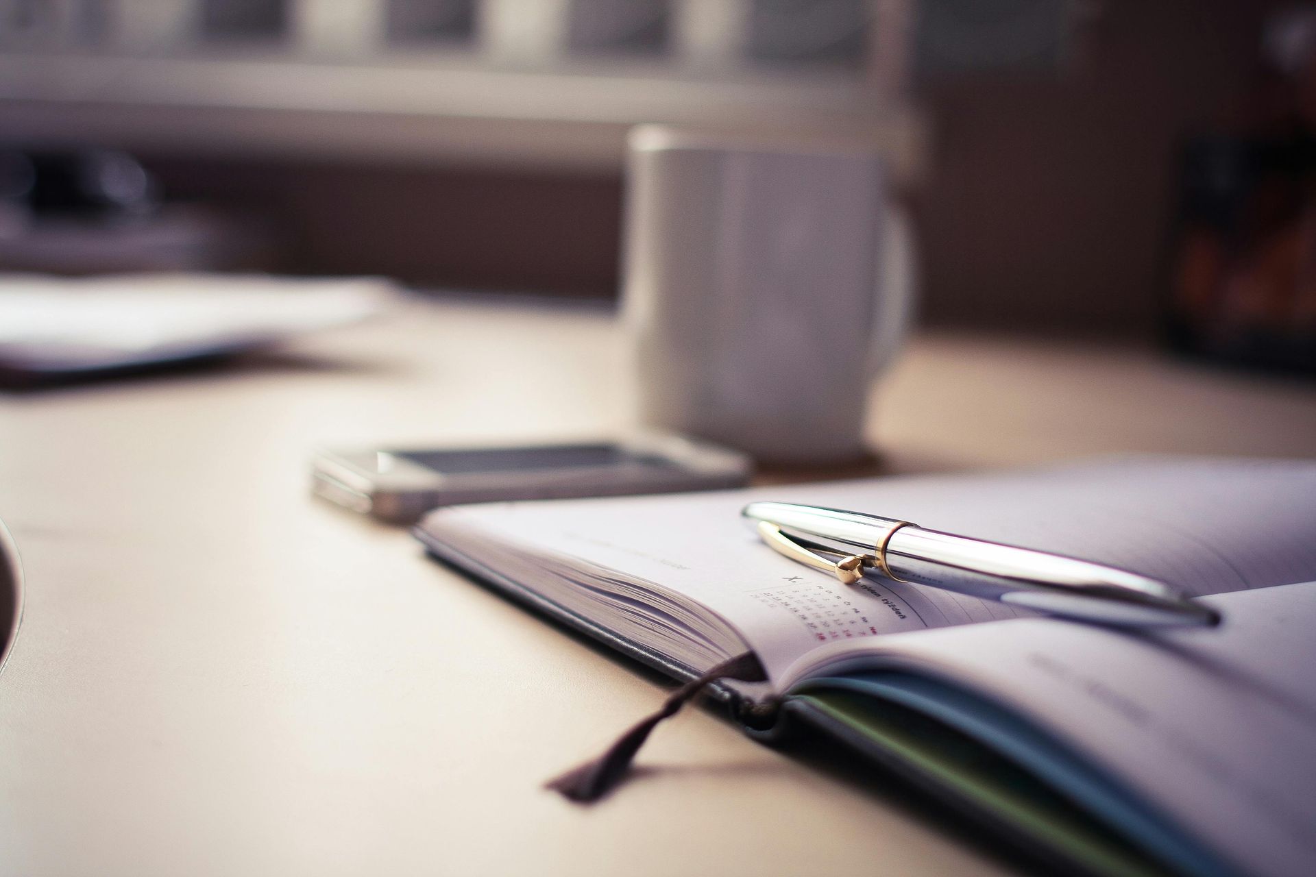 A pen is sitting on top of an open notebook on a desk