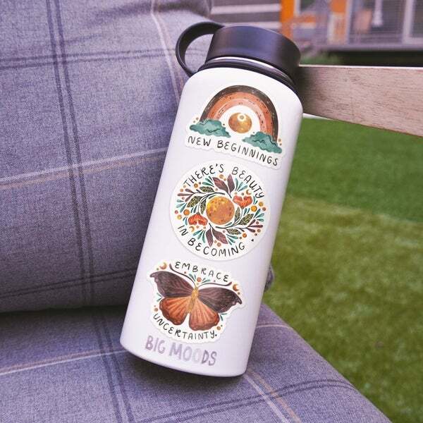 a water bottle with stickers on it is sitting on a couch .