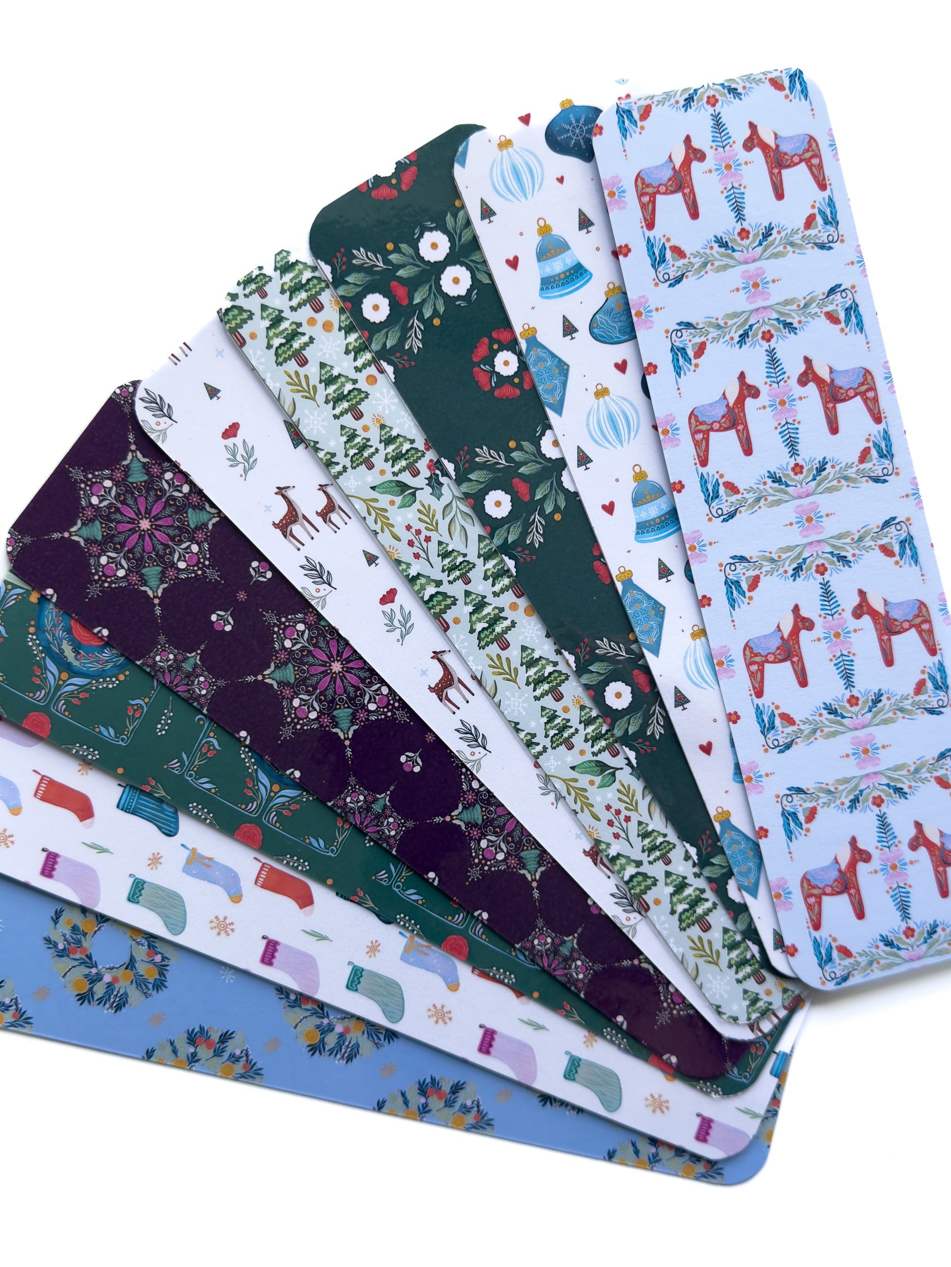 Four bookmarks with flowers and dragonflies on them are sitting on a table.