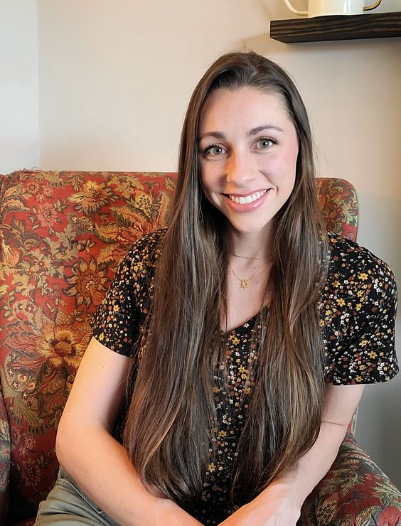 a woman with long hair is sitting in a chair and smiling .