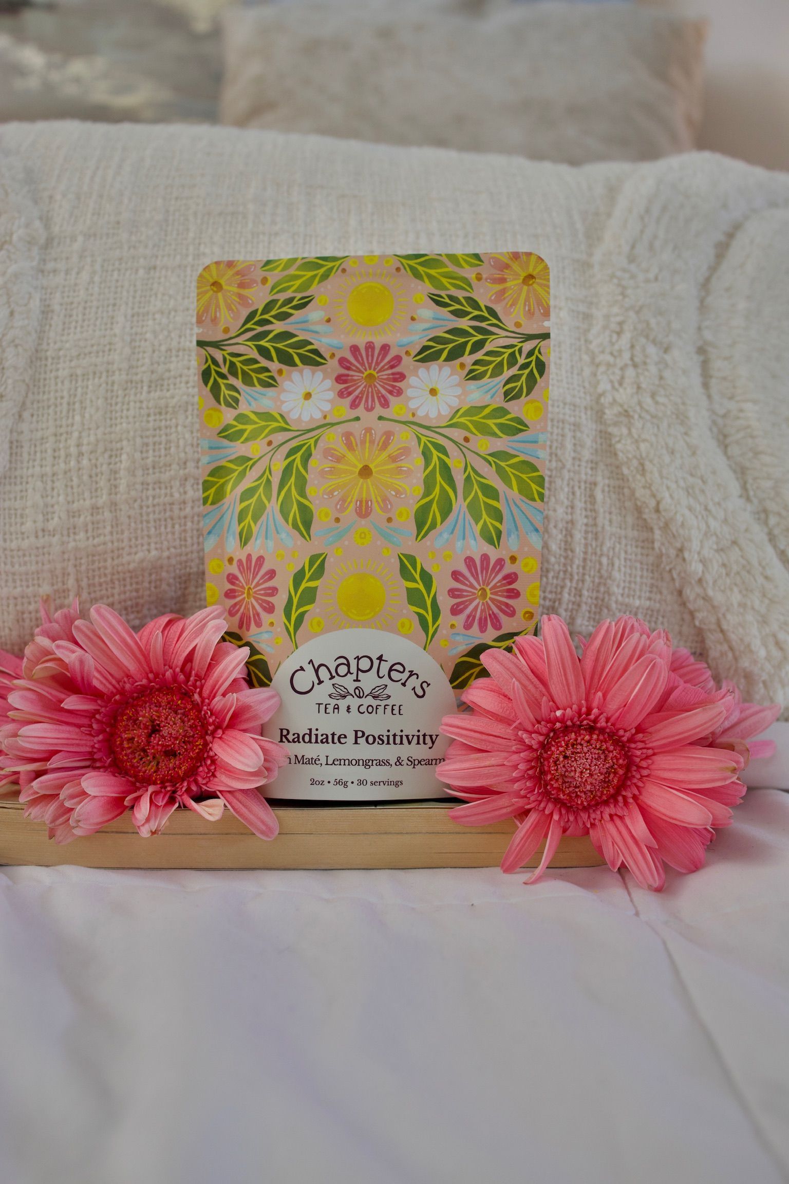 A card with flowers on it is sitting on a table next to pink flowers.