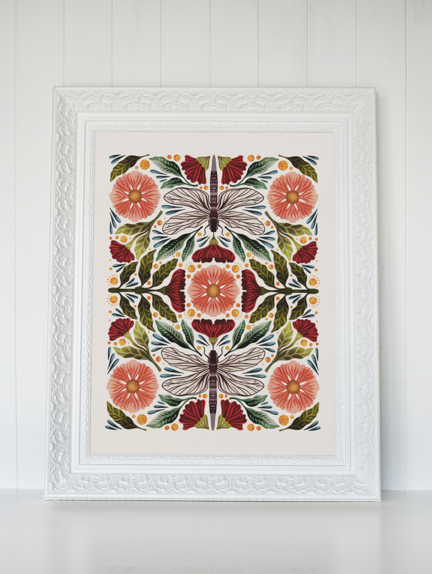 A cross stitch pattern of dragonflies and flowers in a white frame.