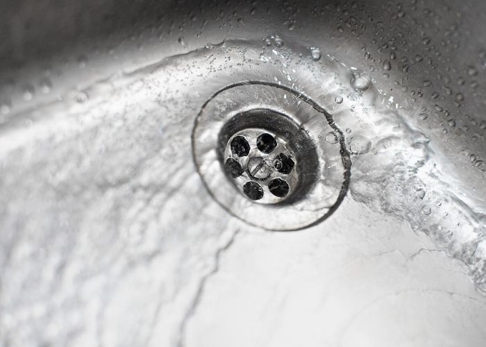 A close up of a sink with water running down the drain.
